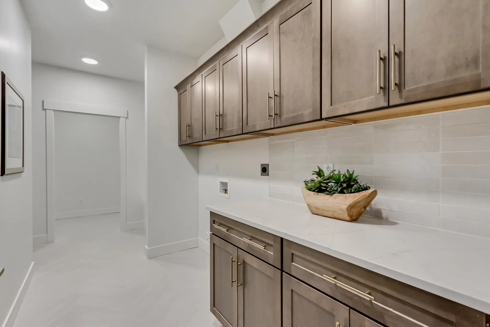 Utility room featuring extensive cabinetry, a light-toned countertop, and a tiled backsplash
