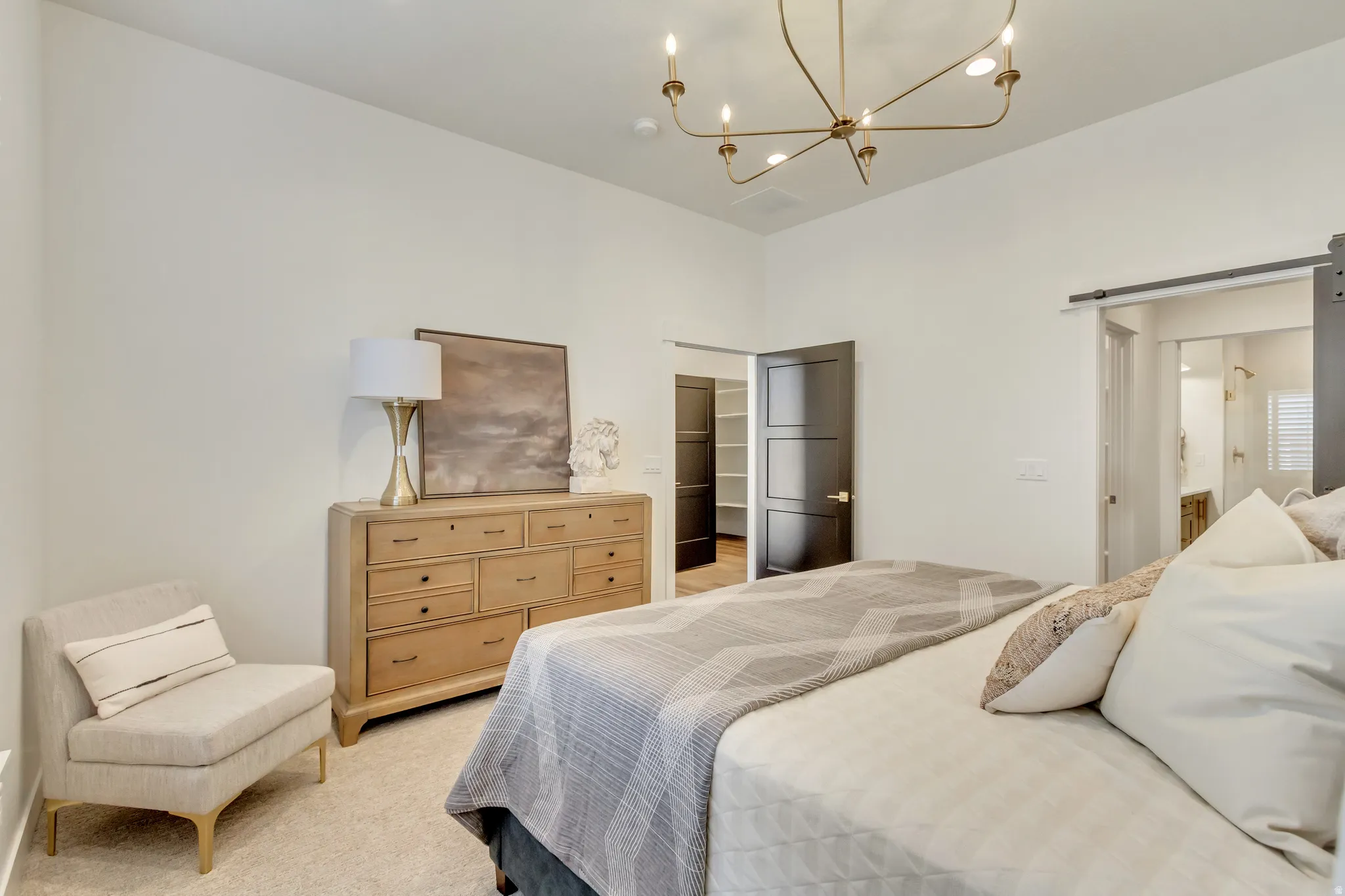 Bedroom featuring a gold-toned chandelier, light-colored walls, and carpet flooring