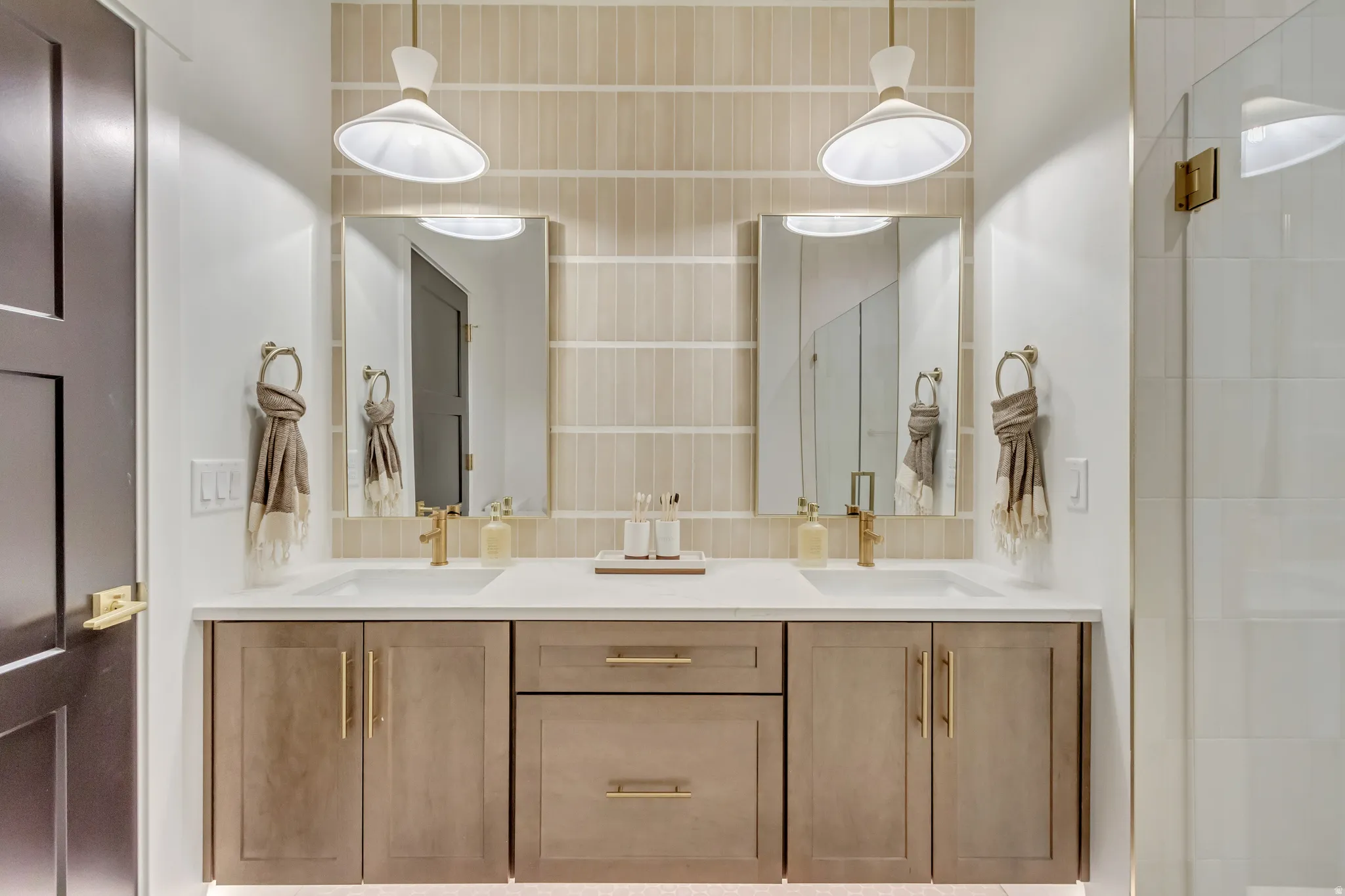 Dual vanity with light wood-finish cabinetry and gold-tone hardware