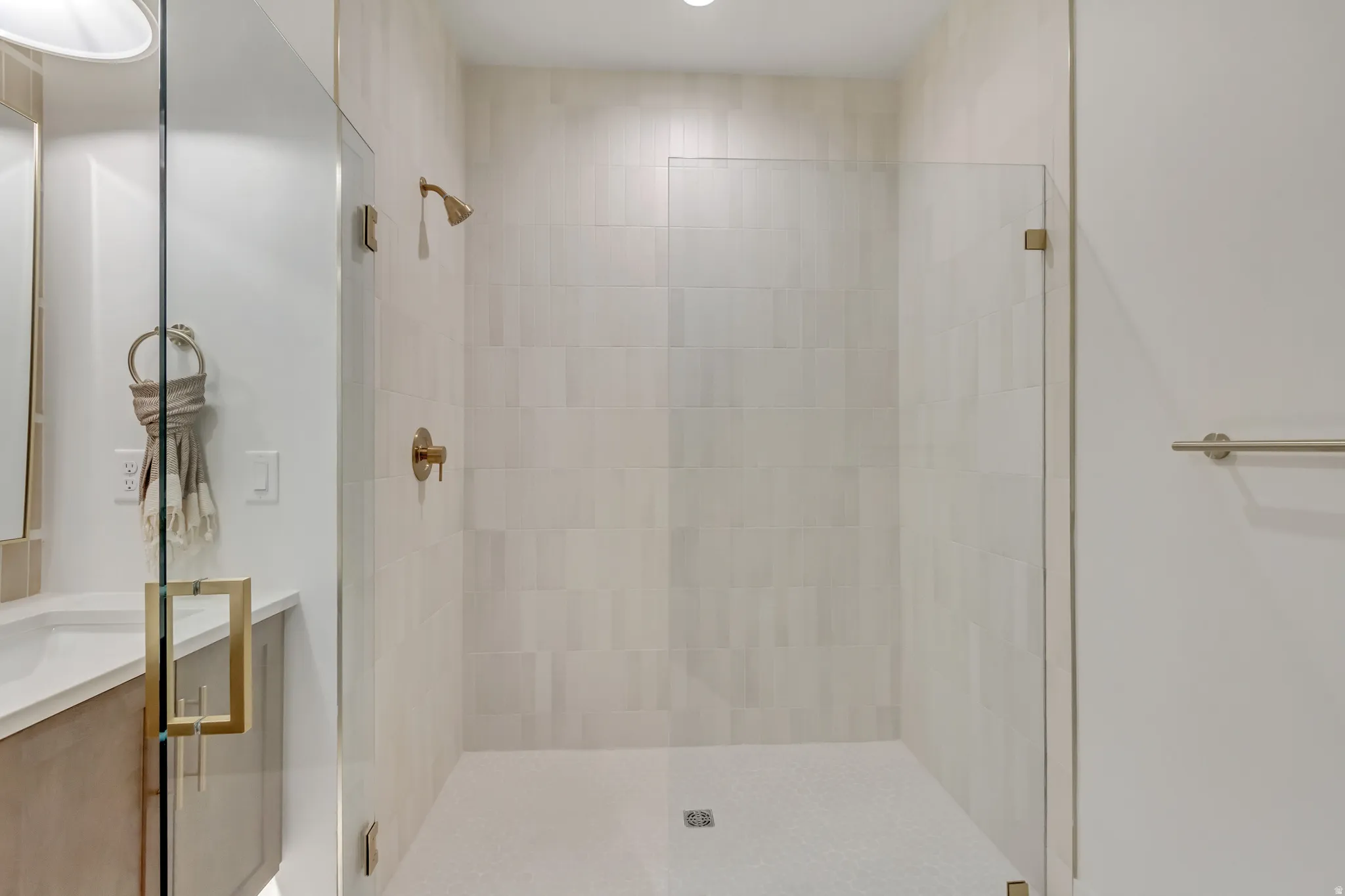 Walk-in shower featuring light-toned rectangular wall tiles and coordinating mosaic floor tiles