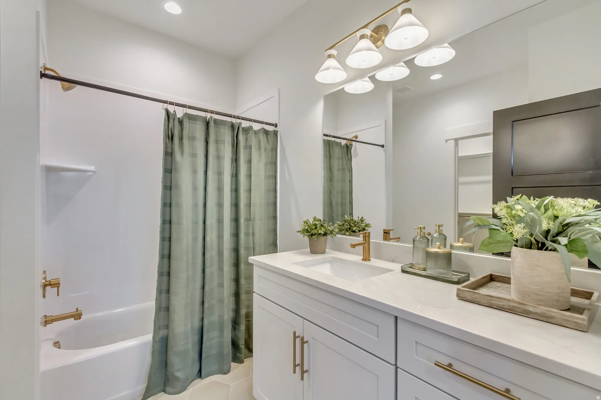 Bathroom featuring a white vanity with white countertop, integrated sink, and brass-finish hardware