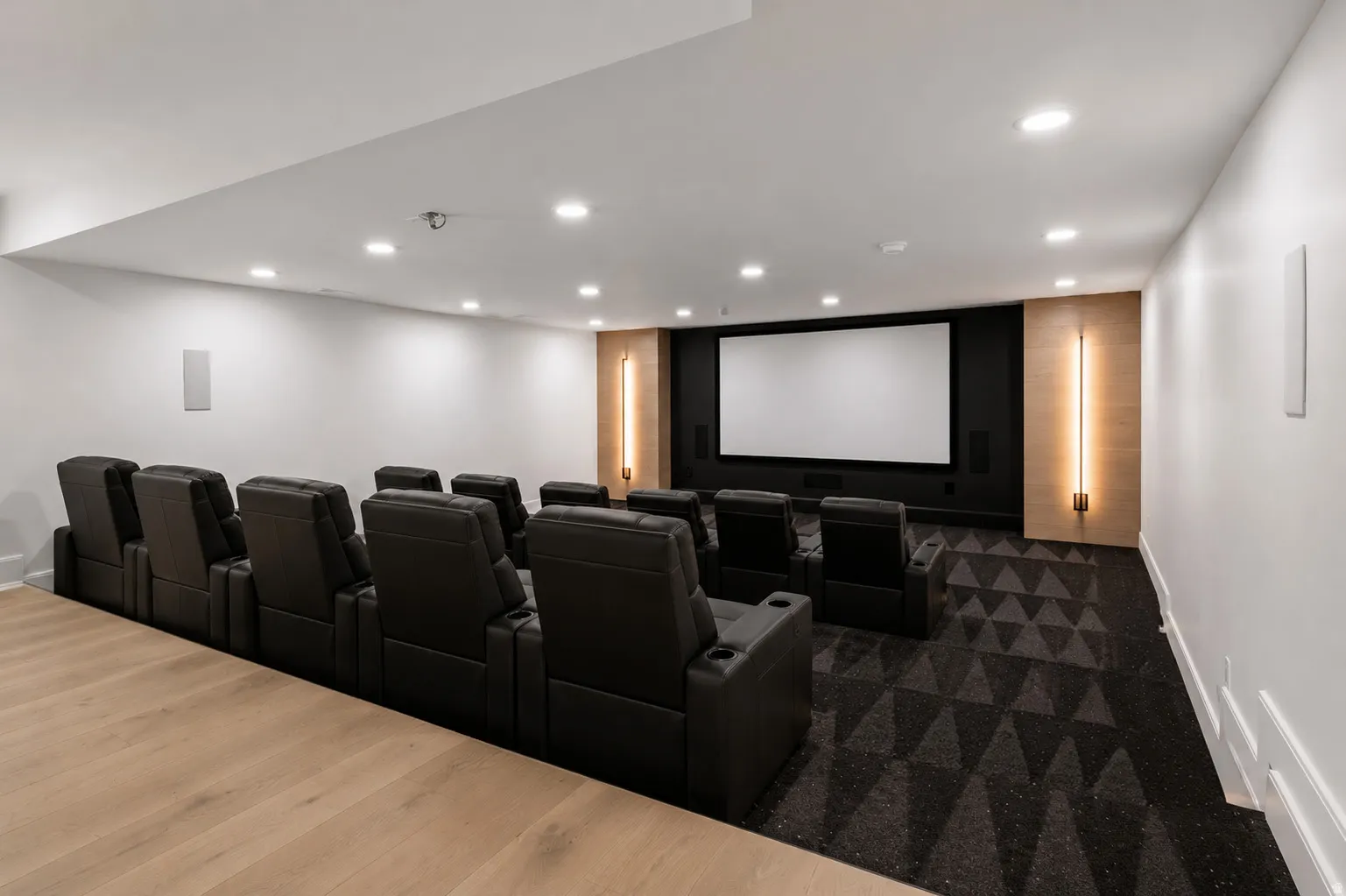 Virtually staged dedicated home theater featuring a large projection screen, recessed lighting, and integrated wall speakers