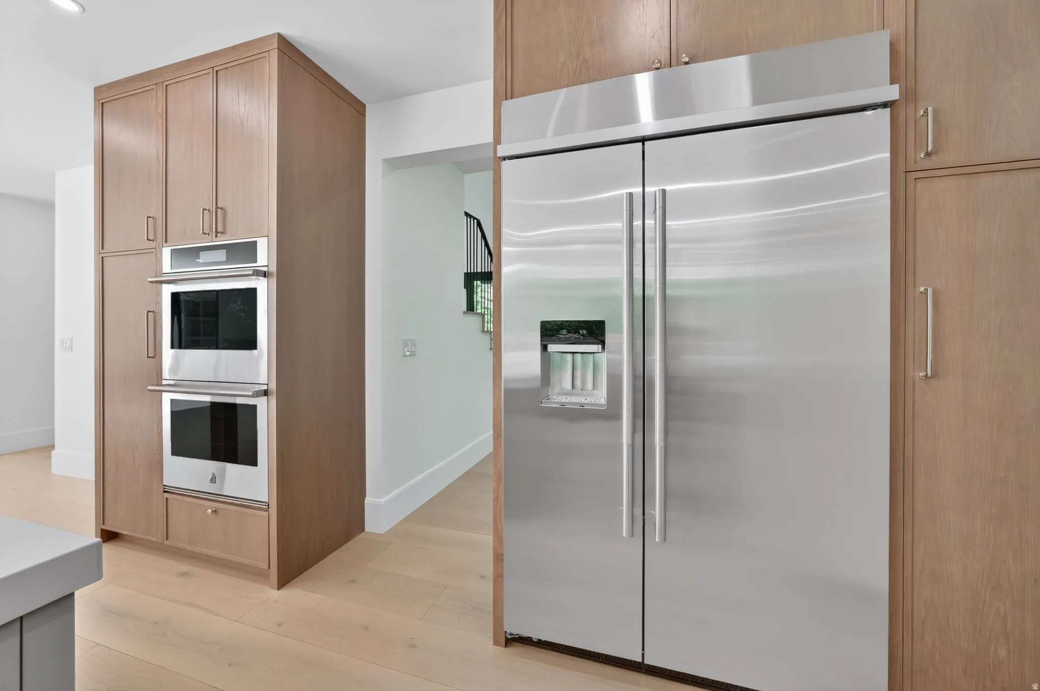Stainless steel side-by-side upgraded all black refrigerator, built-in double ovens, and extensive wood-finish cabinetry