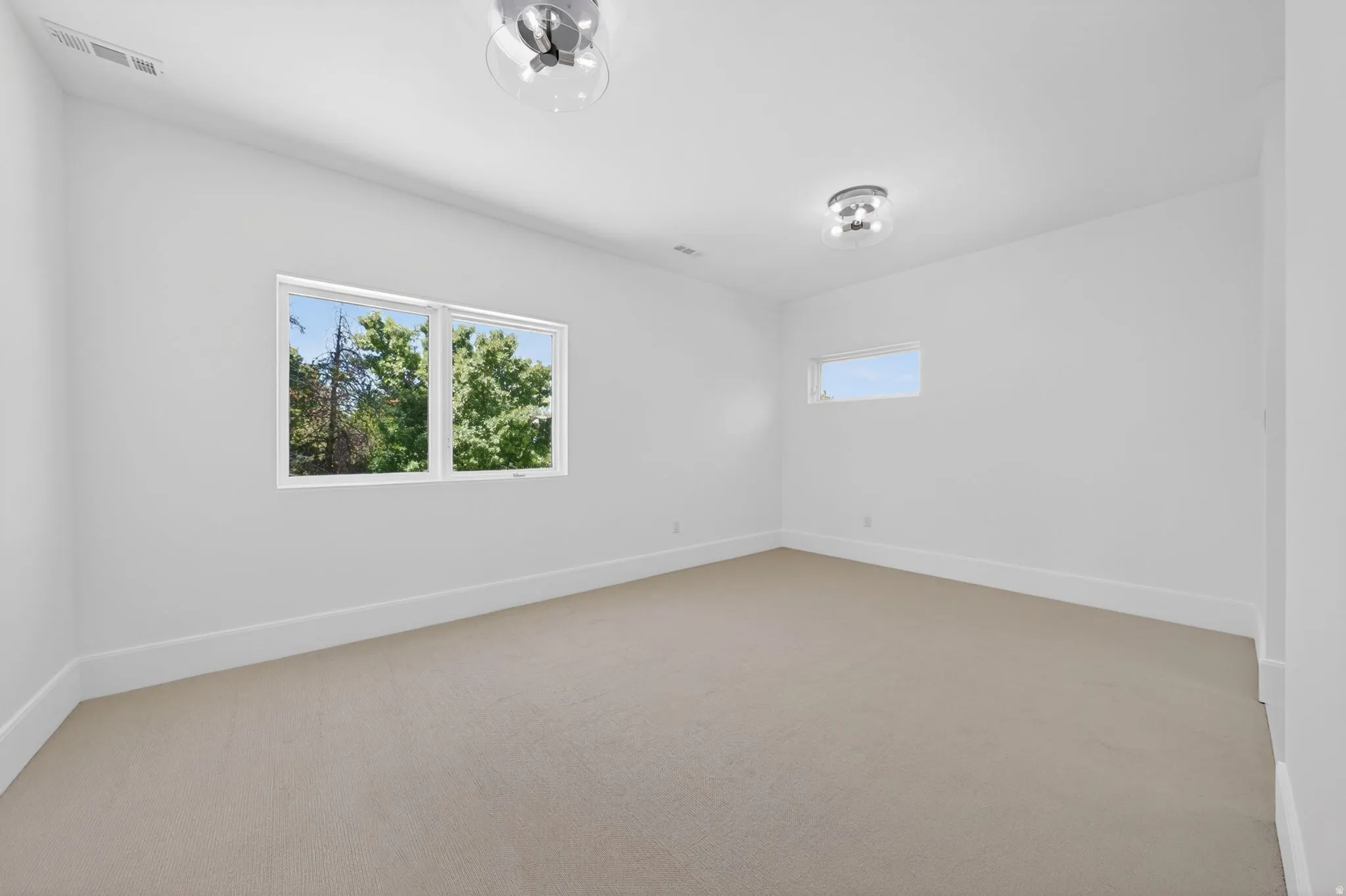 Carpeted room featuring large windows, a secondary horizontal window, white baseboards, and two flush-mount light fixtures