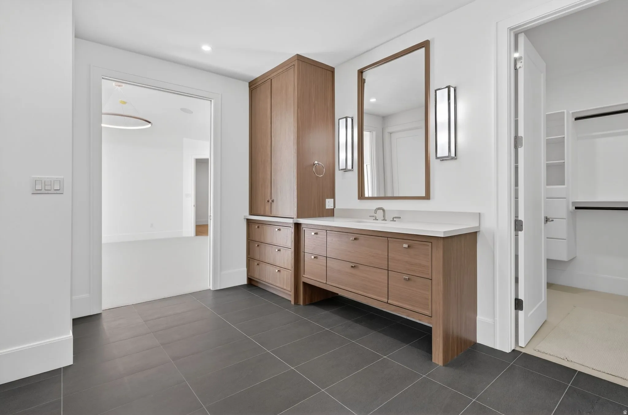 Bathroom featuring a spacious double vanity with anti fog mirrors and wood-finish cabinetry and a light-toned countertop