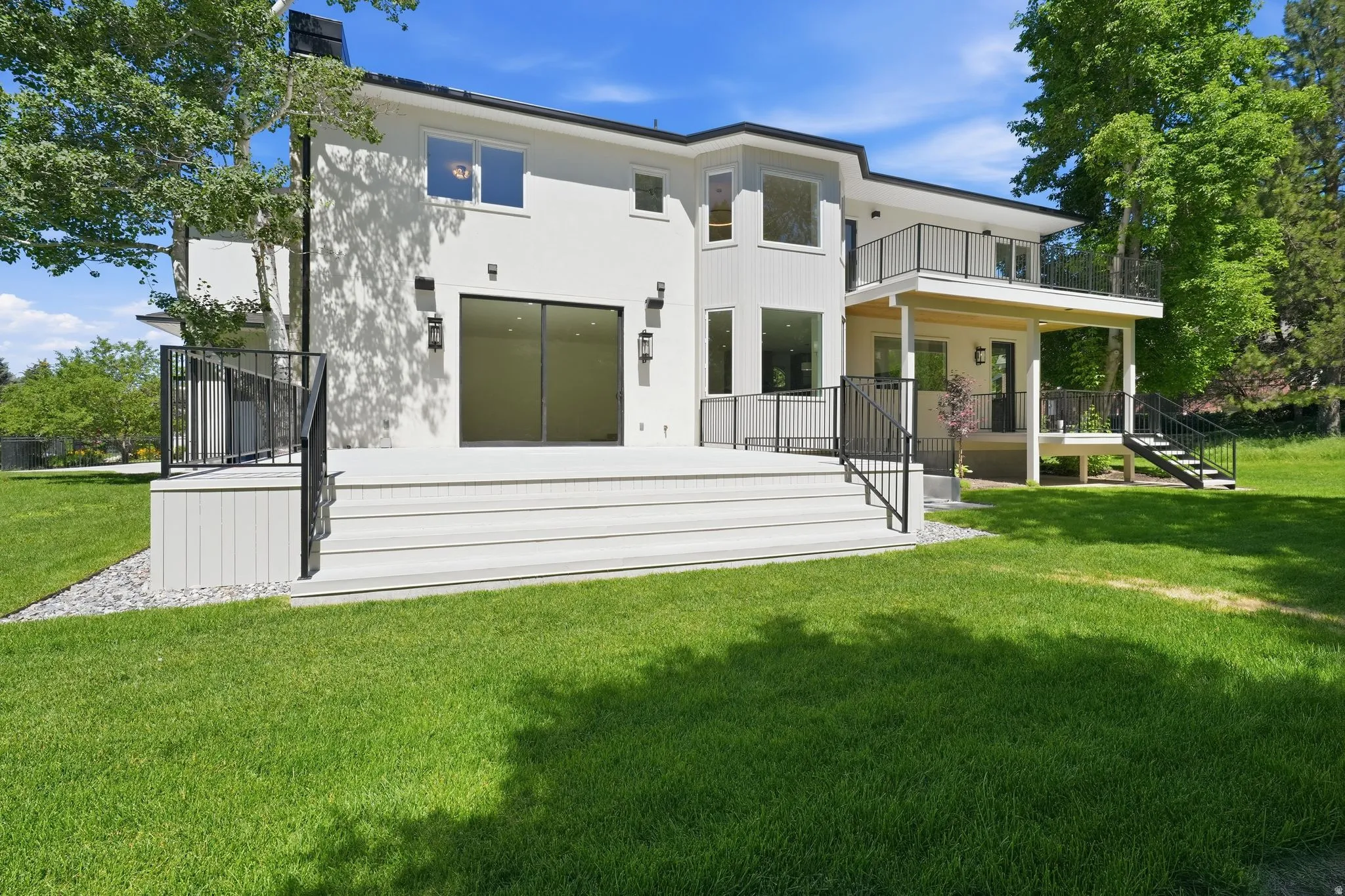 Contemporary white stucco exterior with multiple balconies and a spacious composite deck