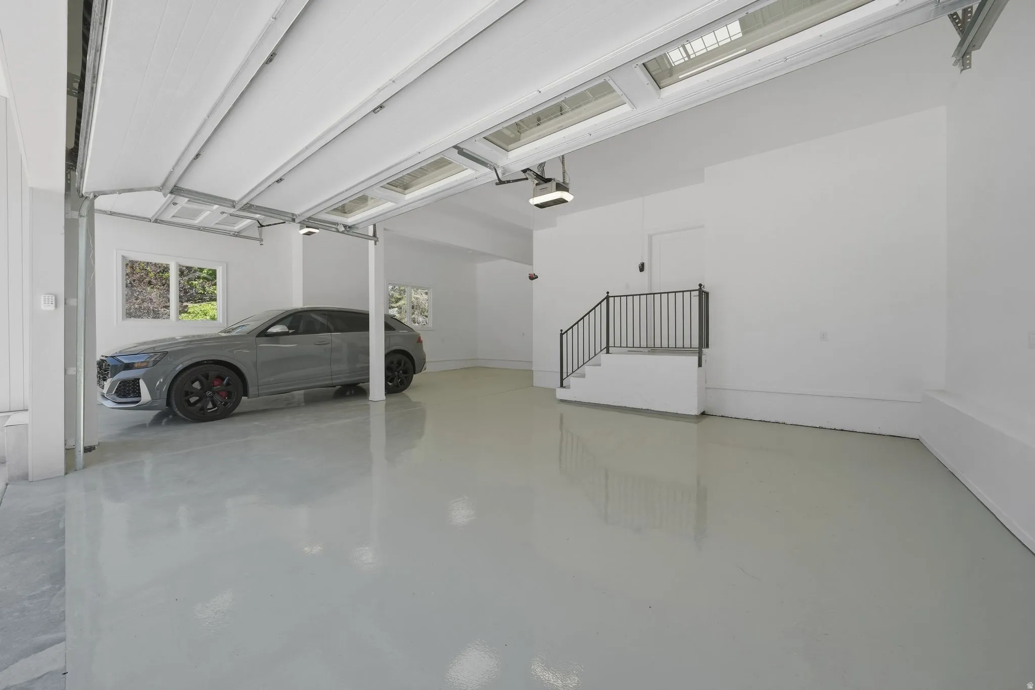 Spacious garage featuring a durable epoxy floor finish, white painted walls, and an overhead garage door with integrated windows