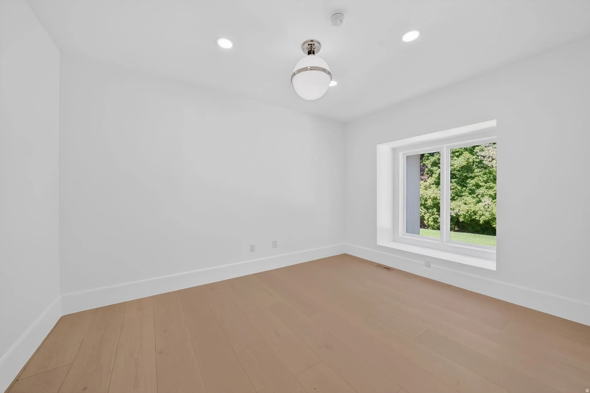 Office space featuring a window with a deep sill, wood-finish flooring, recessed lighting, white baseboards, and a contemporary ceiling fixture
