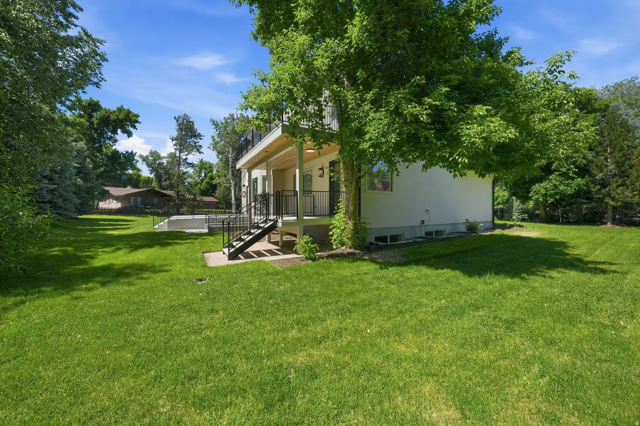 Expansive side yard surrounds the property, featuring mature trees providing natural shade