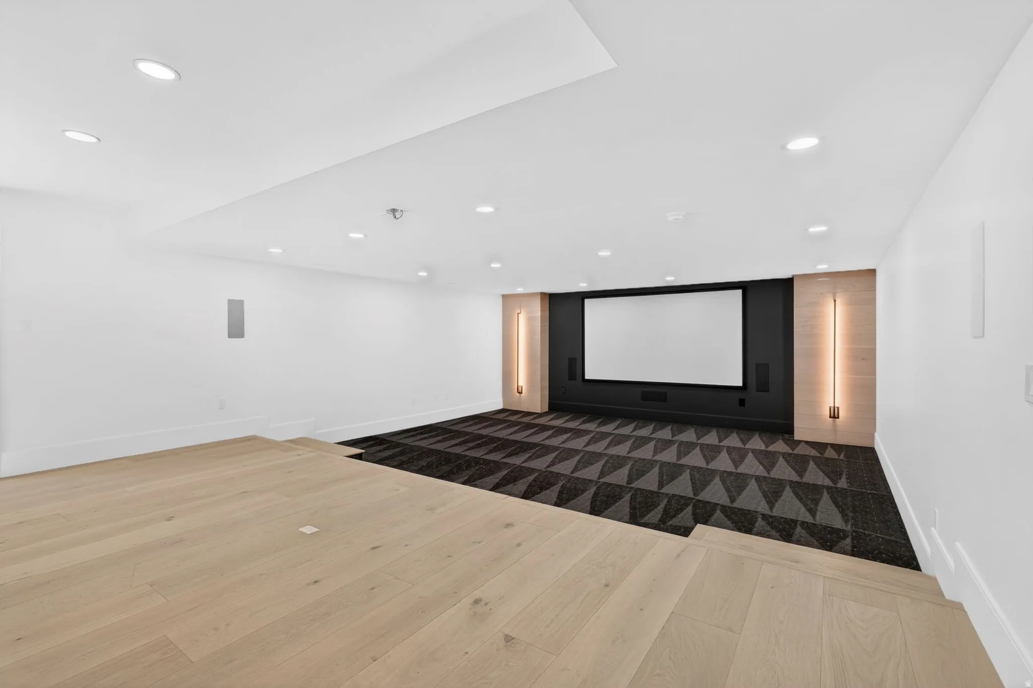 Dedicated theatre room featuring a large projection screen, dark accent wall, and built-in speakers