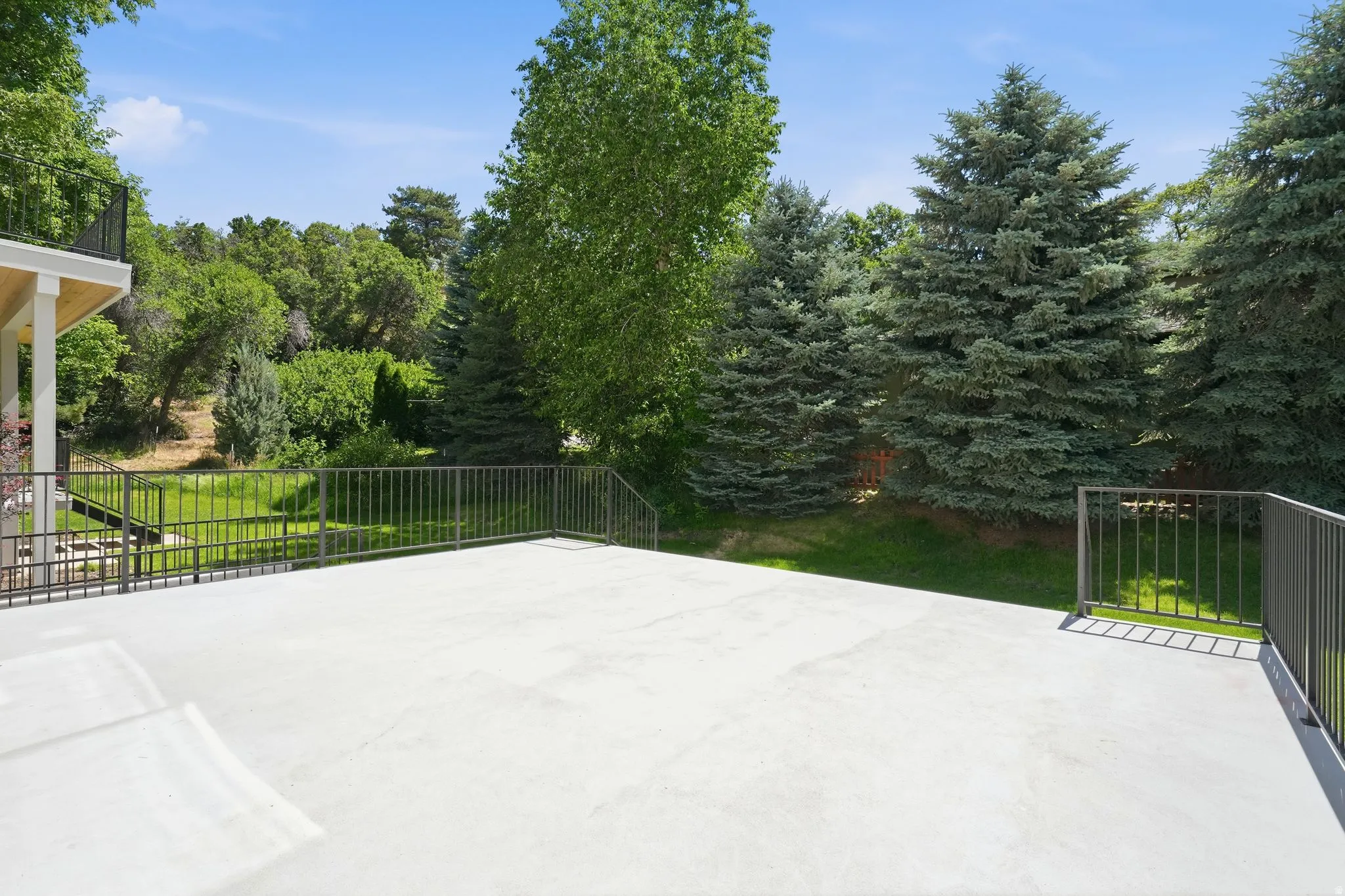Concrete patio outside the living room with metal railings