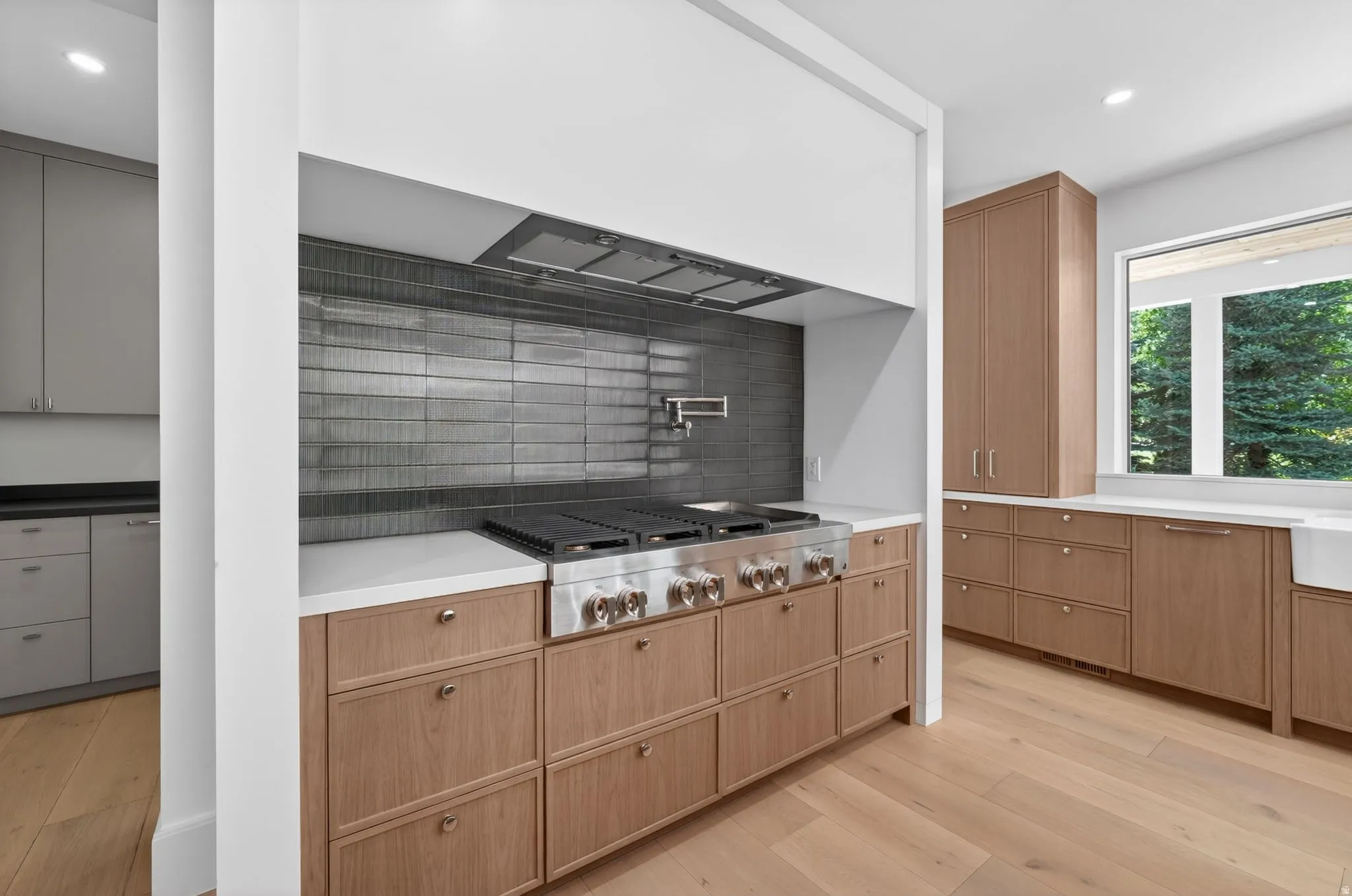 Gourmet kitchen featuring a professional-grade stainless steel range with griddle, a dark tile backsplash, and a wall-mounted pot filler