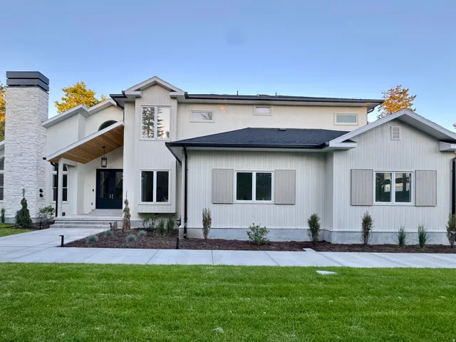 Contemporary exterior featuring a stone chimney, dark paneled entry door, wood-paneled soffit, and horizontal siding