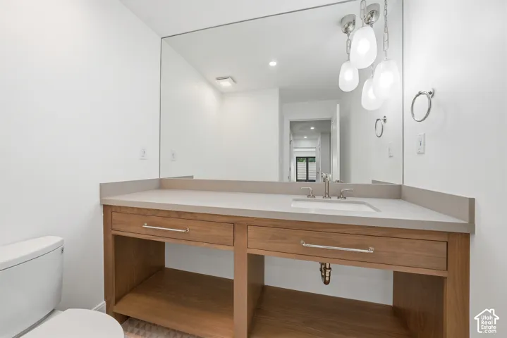 Downstairs bathroom featuring a wood-finish vanity with drawer storage, light-toned countertop, and integrated sink with brushed nickel faucet