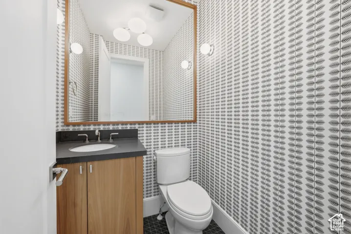 Main level bathroom featuring a wood-finish vanity with a black countertop and undermount sink, a large wood-framed mirror, and a modern ceiling light fixture
