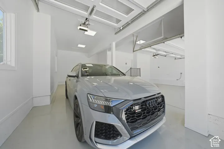 Bright multi-car garage featuring a glass panel overhead door, white painted walls, and light-colored epoxy flooring