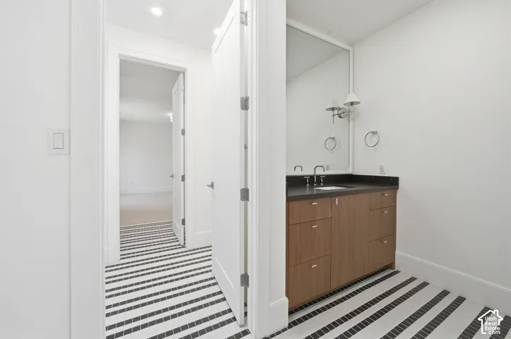 Jack $ Jill bathroom featuring a wood-finish vanity with a dark countertop, undermount sink, and wall-mounted sconce lighting