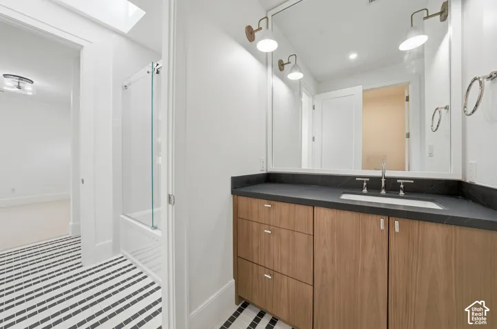 Jack and Jill bathroom featuring a wood-finish vanity with a dark countertop and integrated sink