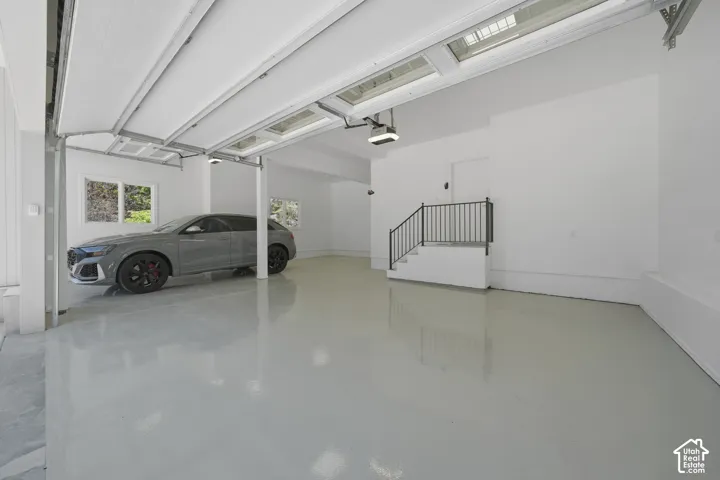 Spacious extra length garage featuring a light gray epoxy floor, white walls, and two windows