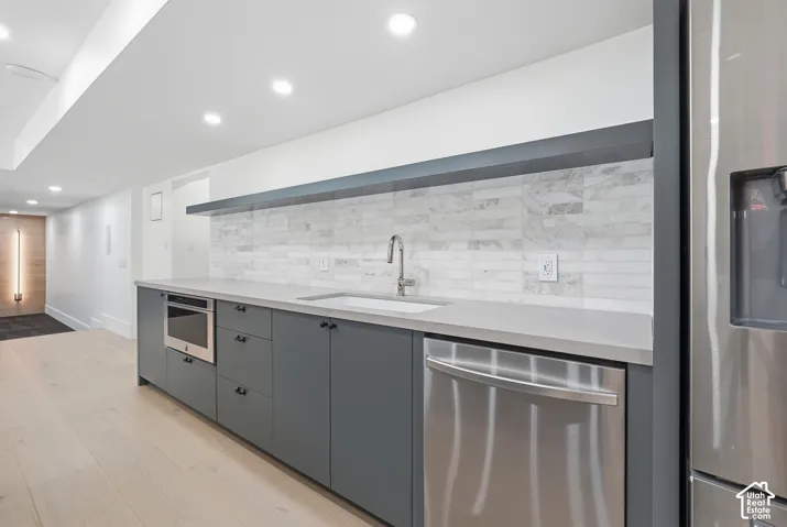 Contemporary kitchen featuring light wood-finish flooring, recessed lighting, and a stainless steel built-in microwave