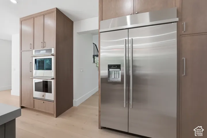 Stainless steel included side-by-side refrigerator, built-in double ovens, and wood-finish cabinetry