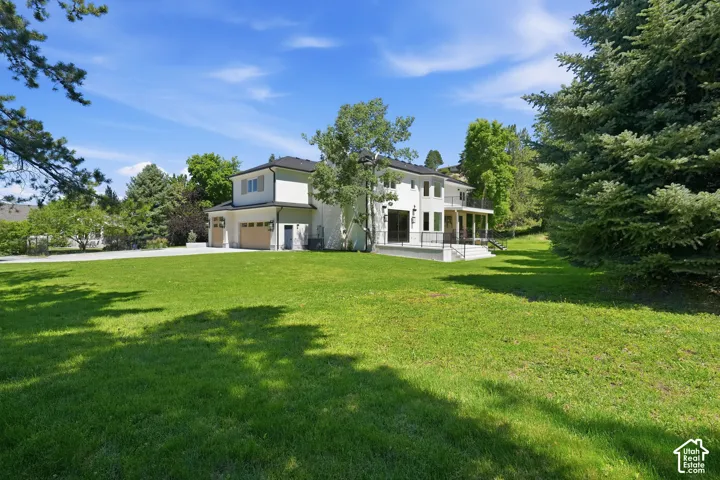Expansive lawn surrounding a modern exterior featuring a black roof, white stucco siding, and multiple balconies with dark railings
