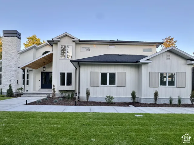 Contemporary exterior featuring a stone chimney, dark paneled entry door, wood-paneled soffit, and horizontal siding