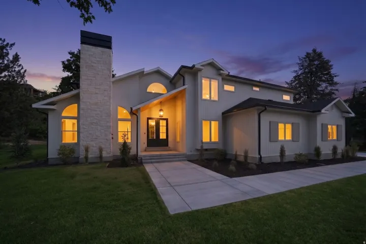 Contemporary stucco exterior featuring a prominent stone chimney, arched windows, and a covered entry