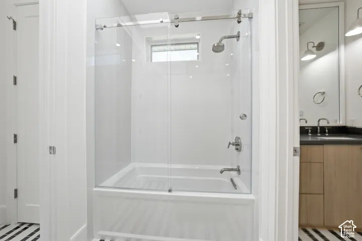Jack & Jill with white tub and shower combination with clear glass enclosure and chrome fixtures