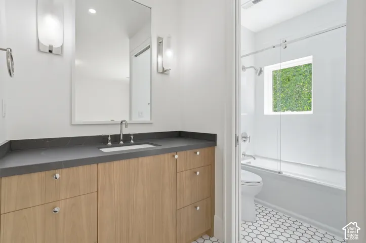 Second bathroom vanity featuring a light wood-finish cabinet, dark countertop, and rectangular undermount sink