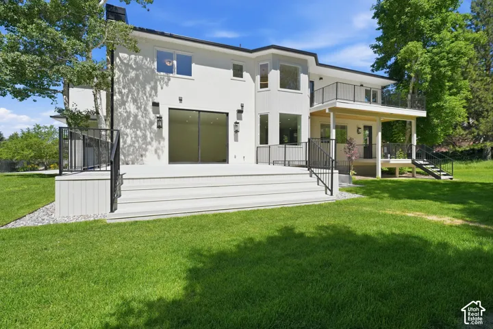 Contemporary back patio with white stucco exterior with multiple balconies and an expansive composite deck