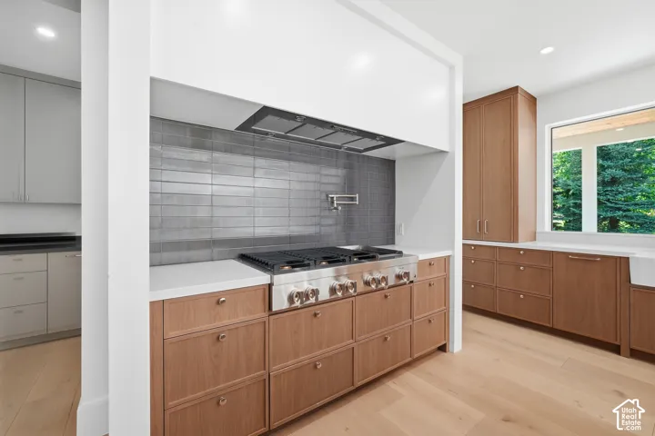 Professional-grade range with a pot filler faucet, complemented by a tile backsplash and custom wood cabinetry