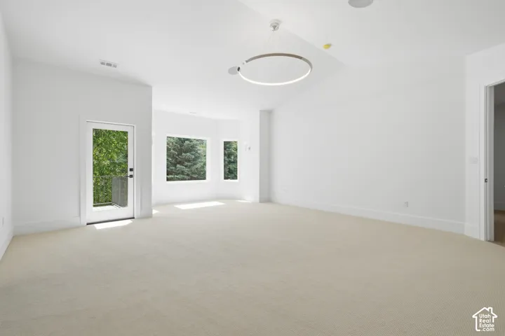 Spacious primary room room featuring neutral carpeting, a modern circular pendant light fixture, and recessed lighting