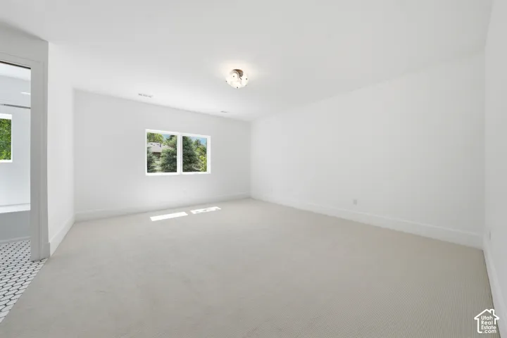 Spacious second bedroom with light-toned carpeting and white walls