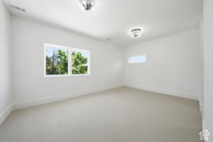 Carpeted third bedroom featuring a large horizontal window and a high transom window, providing natural illumination