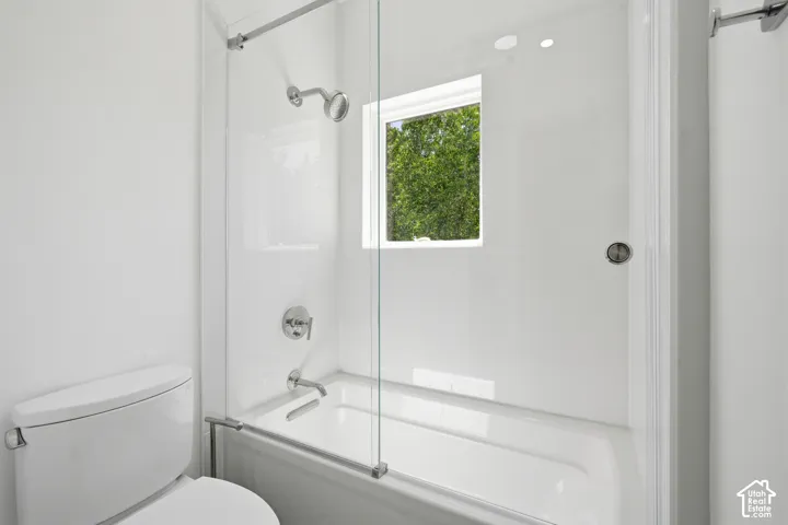 Second bathroom featuring a white bathtub, glass shower enclosure, chrome fixtures, and a window
