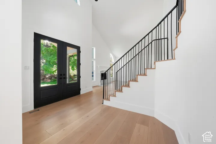 Double-height front door entryway featuring a modern staircase with black iron spindles and light wood treads