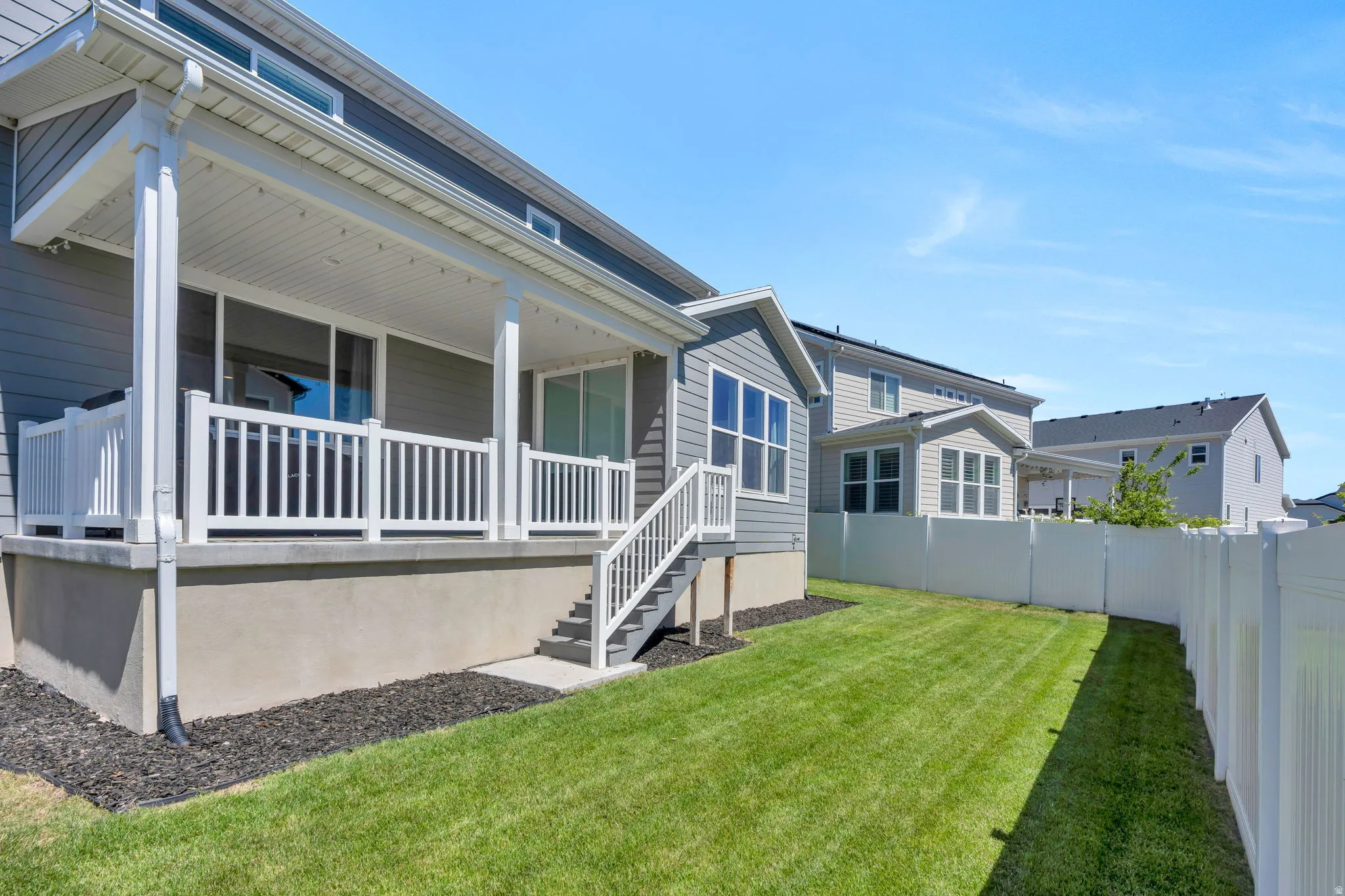 Covered patio with white railing and steps to the backyard