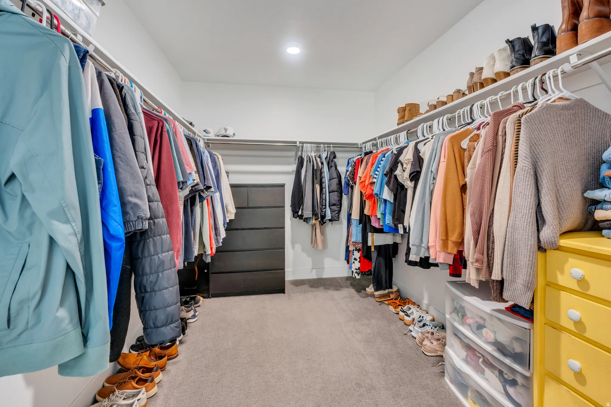 Walk-in closet featuring built-in shelving, hanging rods, recessed lighting, and soft carpet flooring