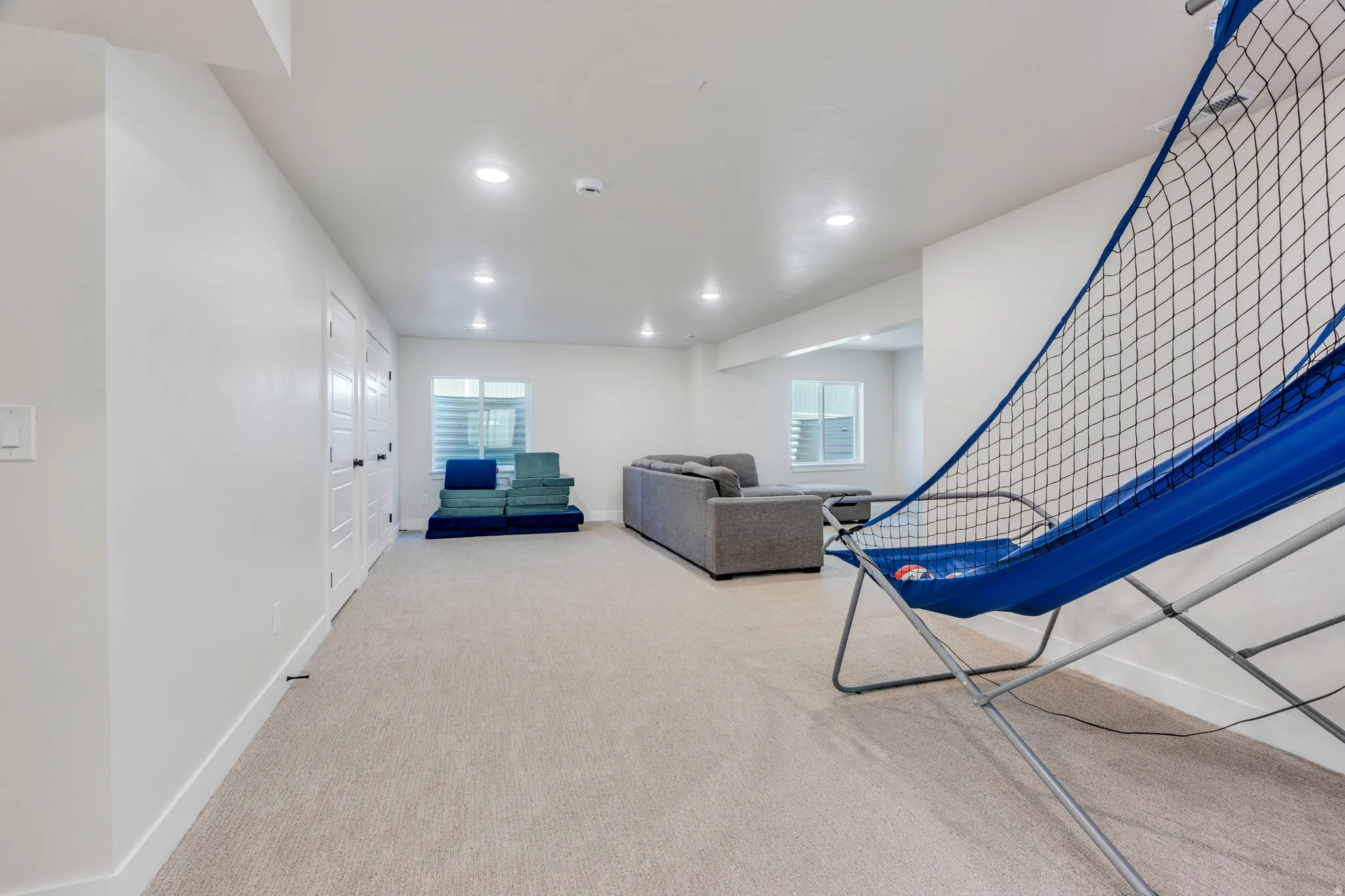 Spacious room featuring light-colored carpeting, recessed lighting, and bright white walls
