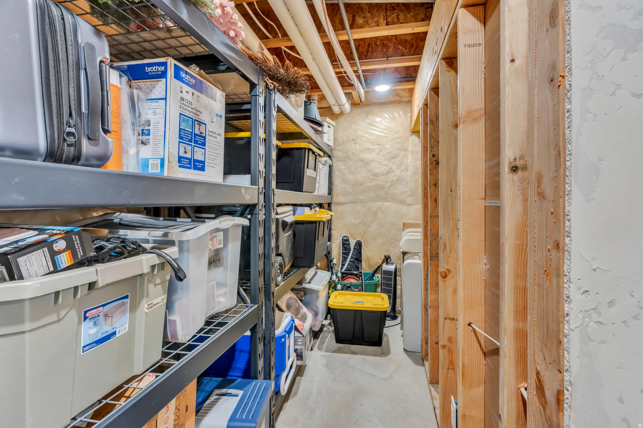 Unfinished basement space featuring exposed wooden framing, concrete flooring, and visible ceiling utilities