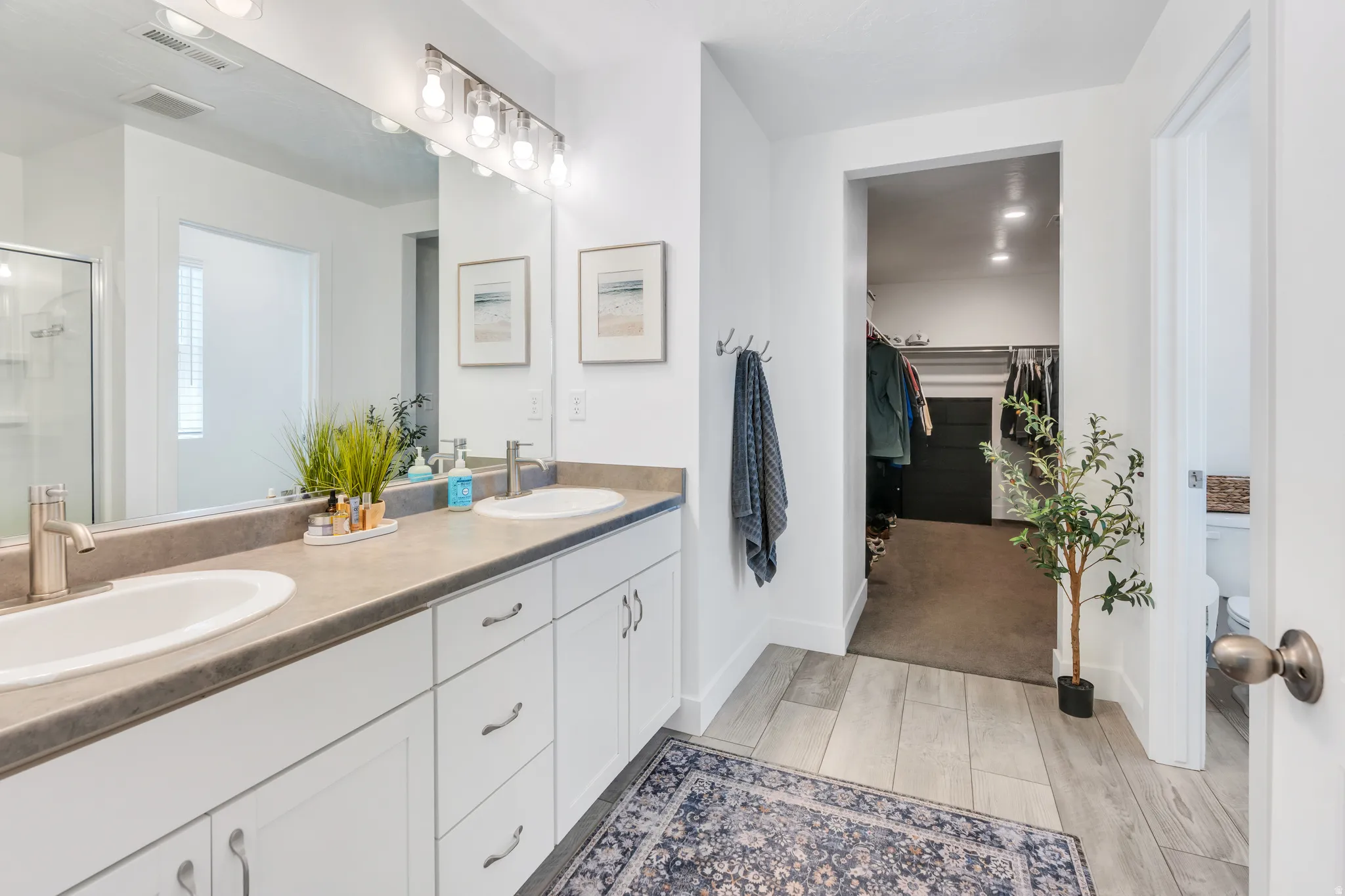 Bathroom featuring a double vanity with two undermount sinks, brushed nickel faucets, and a large wall-mounted mirror