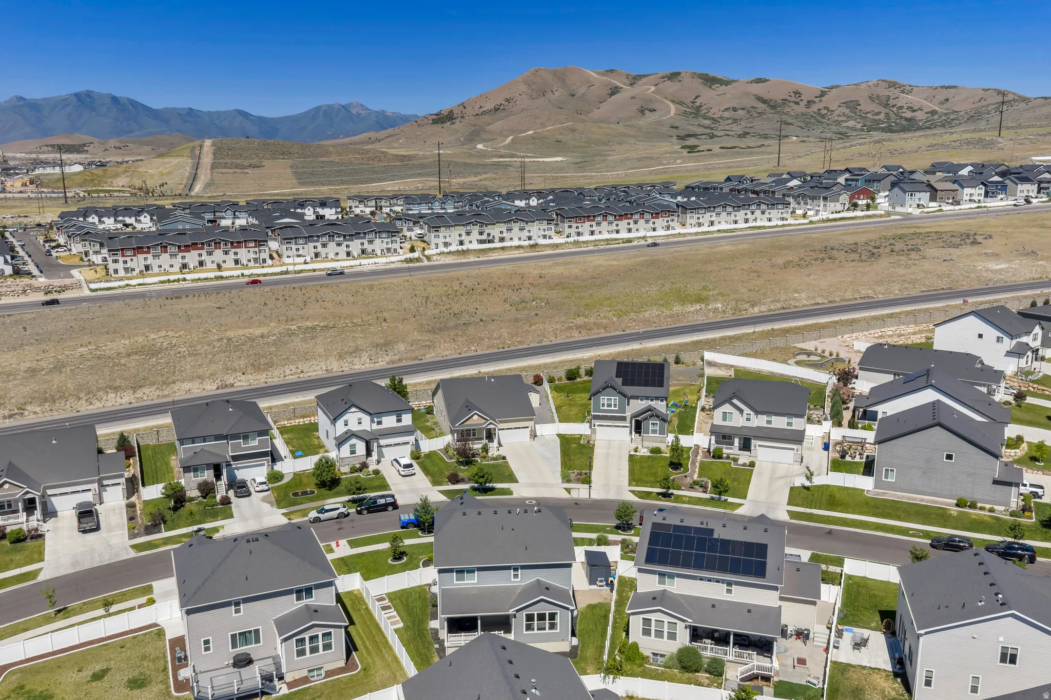 Aerial perspective showcasing a residential development with varied single-family homes and multi-story buildings, featuring paved roads and landscaped green spaces