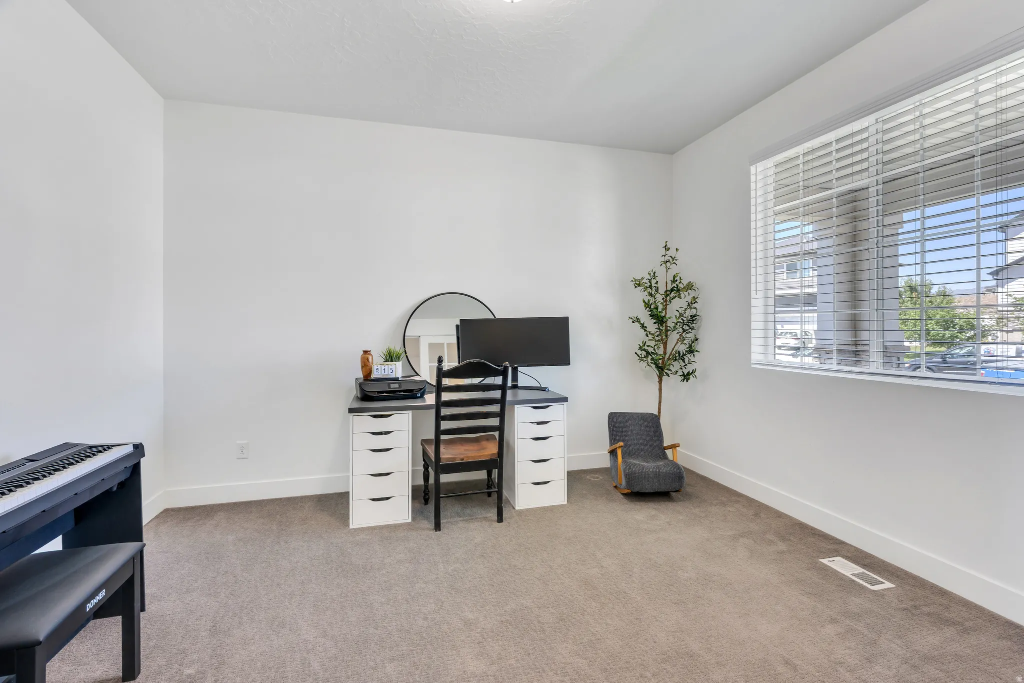 Carpeted room with a large window featuring horizontal blinds