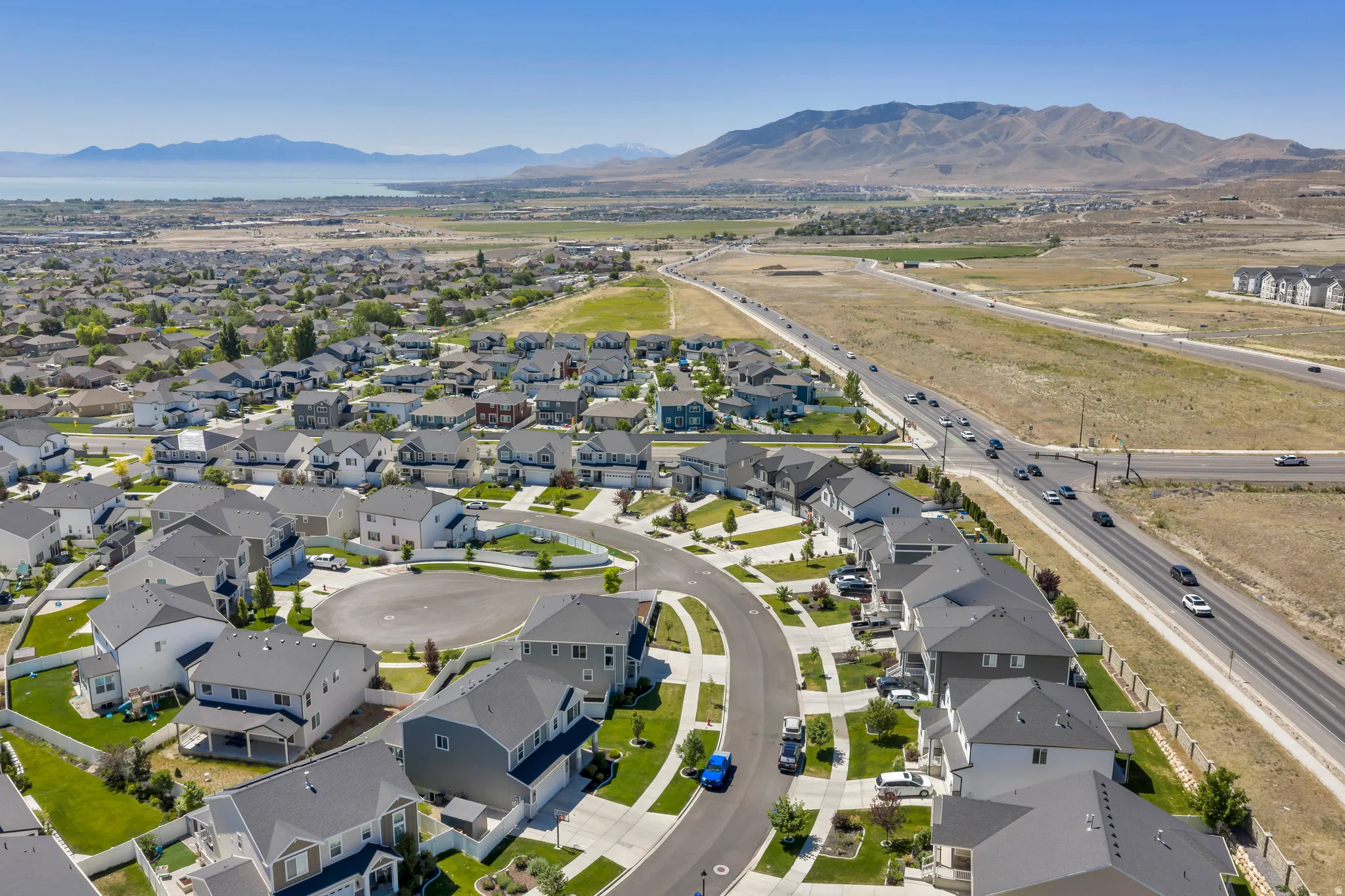 Expansive residential development featuring contemporary homes with gray and white exteriors, asphalt shingle roofs, and attached garages