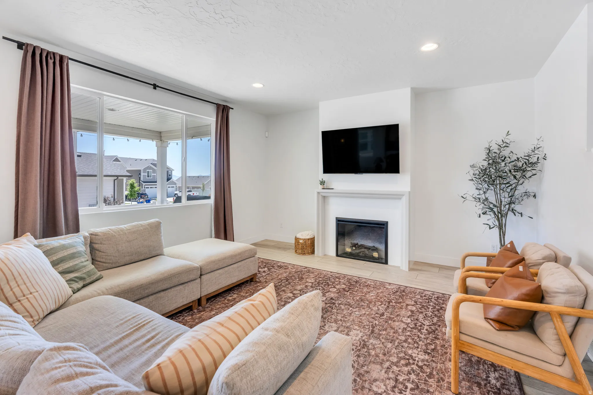 Bright living area featuring a wide window with a dark curtain rod, recessed ceiling lighting, and light-toned flooring