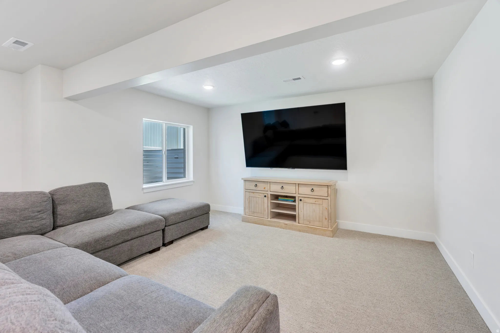 Carpeted entertainment area featuring recessed lighting, a window with horizontal blinds, and a built-in media console