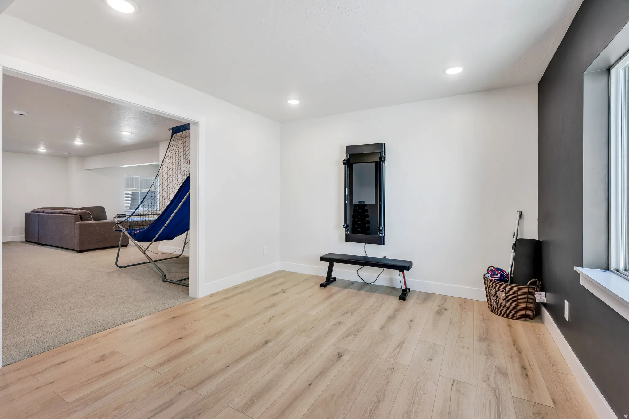 Open-concept room featuring light wood-finish flooring, recessed lighting, and a window with white trim