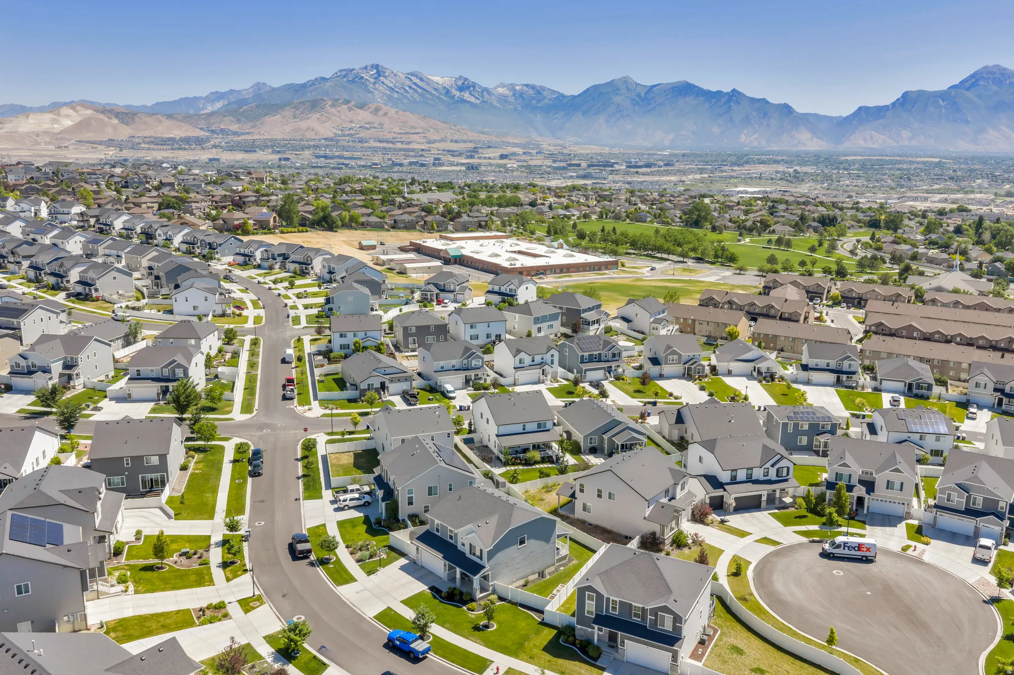 Residential development featuring a variety of single-family homes and townhomes, complemented by manicured lawns and paved streets