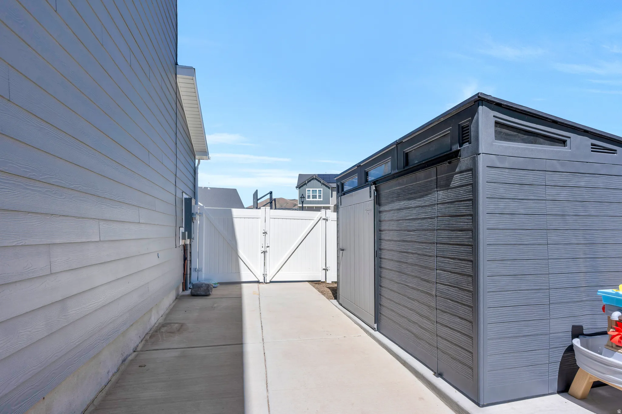 Concrete pathway with white vinyl fencing and a contemporary shed